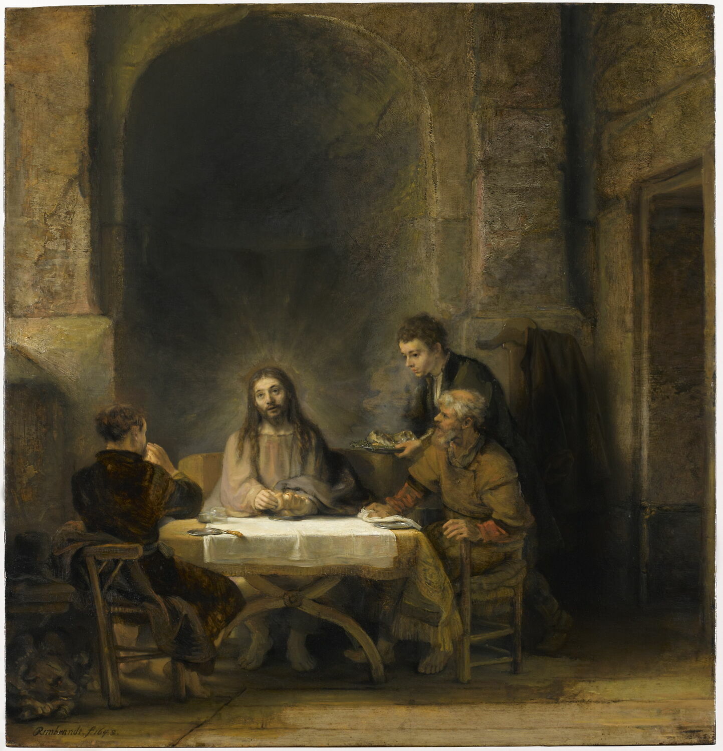 A painting shows three men seated at a table inside a vaulted stone interior. Jesus sits in the center facing the viewer and wearing a light green-gray robe, light emanating from his head. To his left is a young man with his back mostly turned to the viewer, and to the right is an older man sitting in profile. A young servant stands offering a tray to the table.