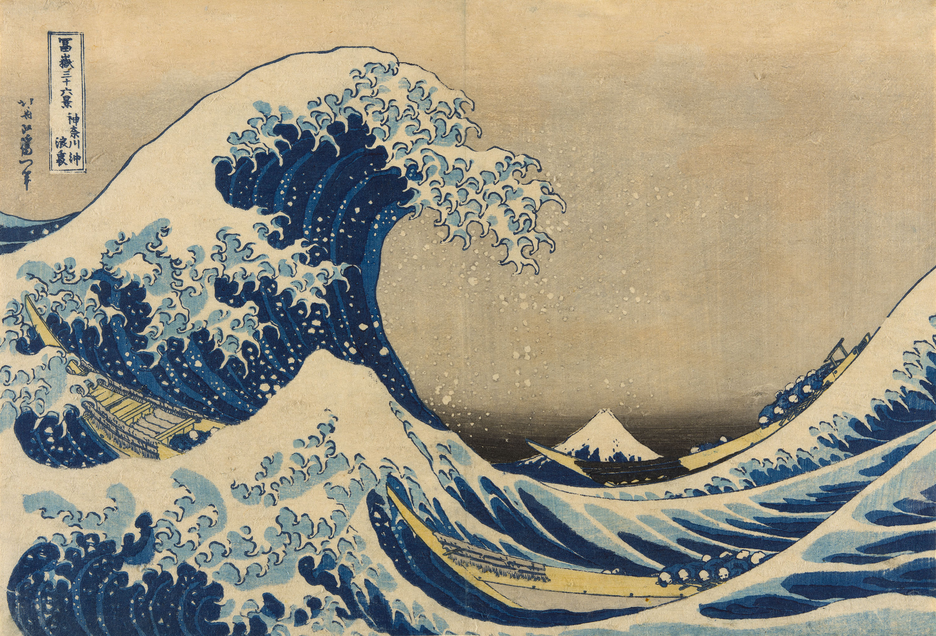 A color print features an enormous, highly animated wave with white peaks rising at left, poised to crash down at right. Beneath it is a long rowboat, and in the distance at right is a cone-shaped mountain, Mount Fuji.