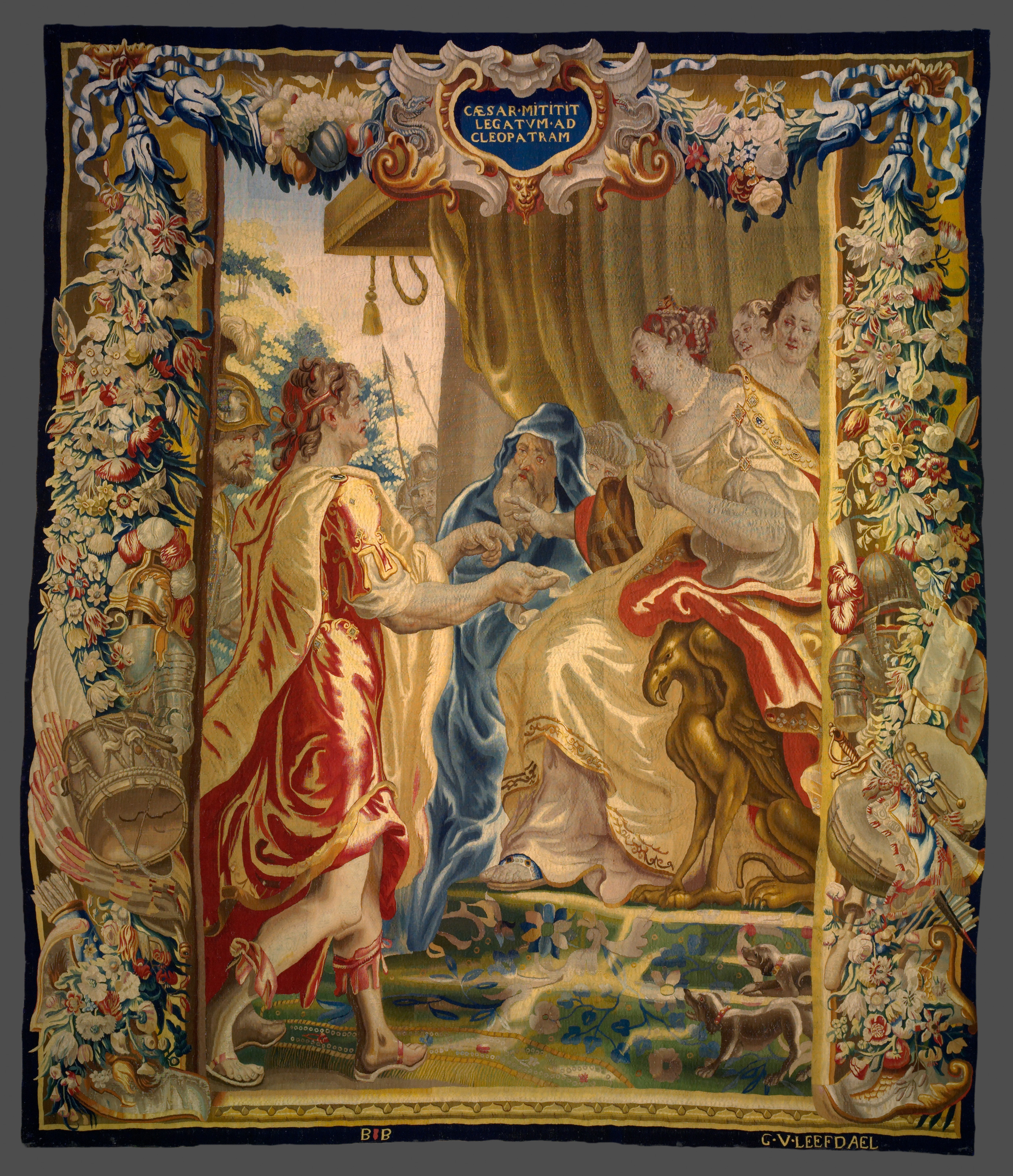 A large tapestry with an ornate border featuring a man approaching a woman in a large throne.