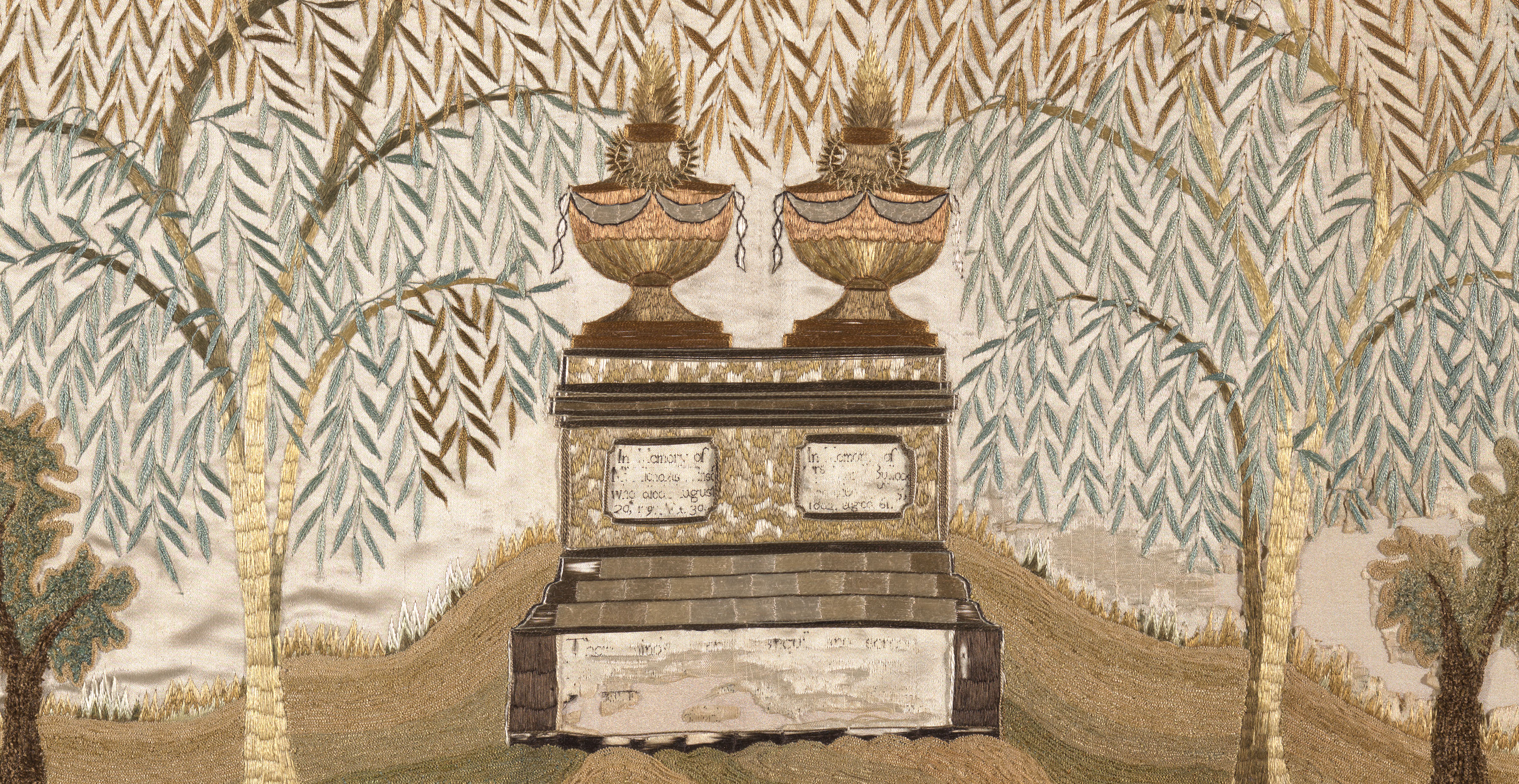 An embroidered textile in shiny green and brown thread shows a gravesite with a rectangular stone topped with two unlike structures. Two plaques on the stone are embroidered with text, much of it missing. Willow trees and their leaves fill the background.