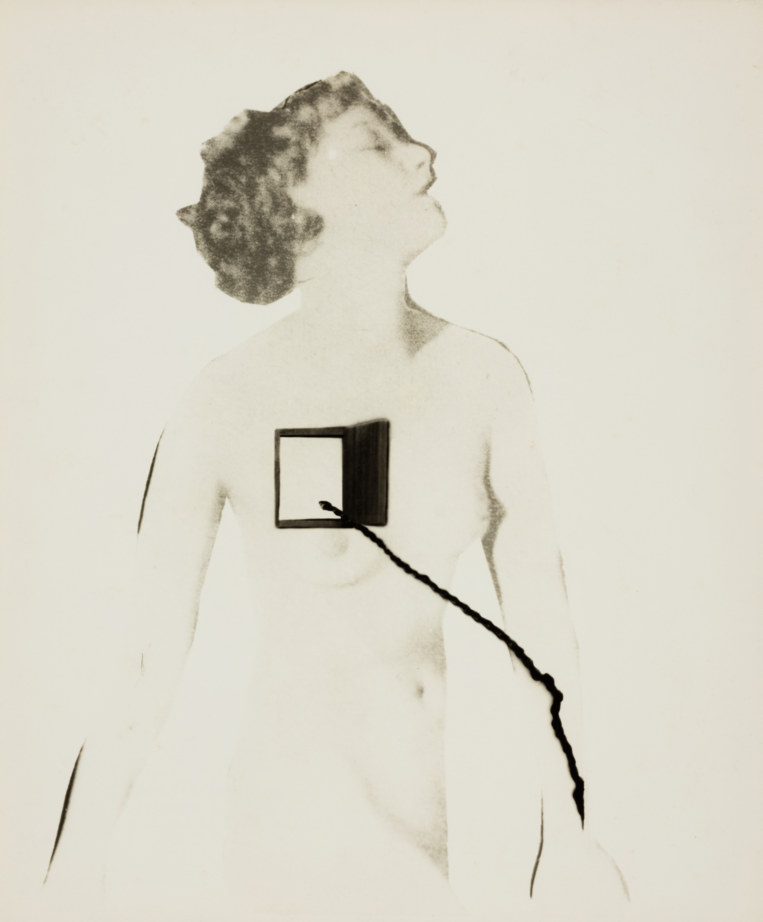 A portrait-oriented black-and-white photograph shows a light-skinned nude woman from the thighs up, her head thrown up and to the side. The exposure is such that her skin matches the white of background. Super-imposed on the right side of her chest is a small rectangular black container that is opened with what appears to be a cord dangling from it.opened