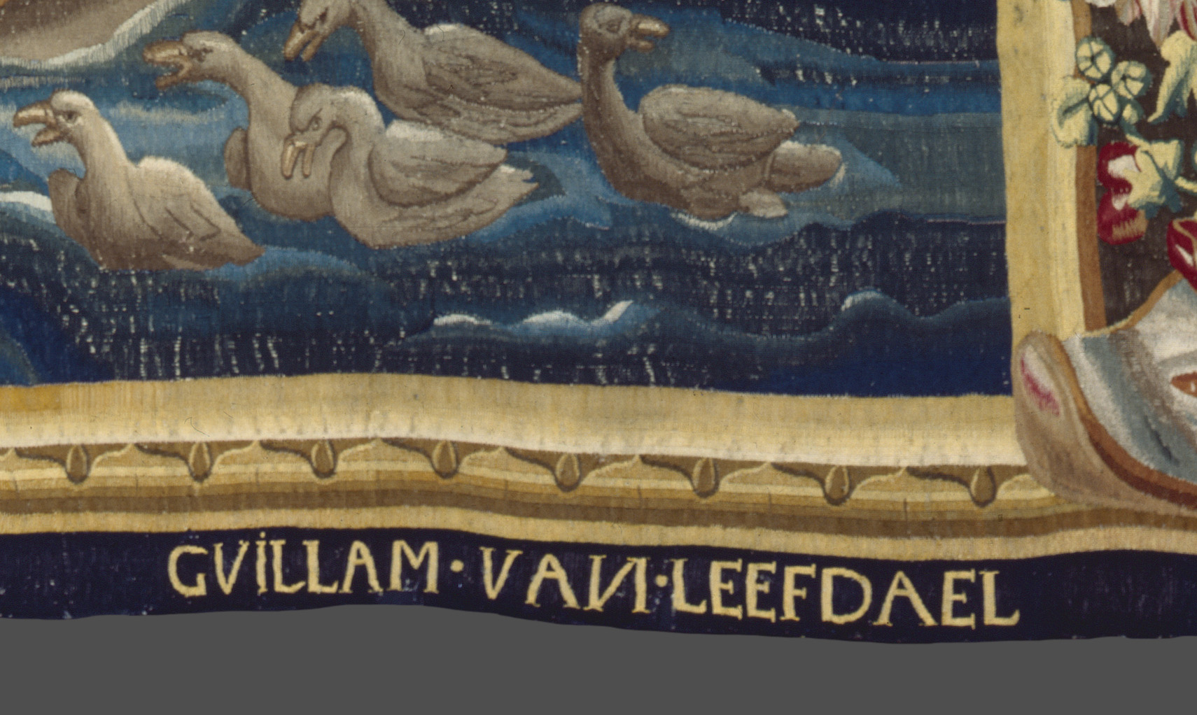 A detail of a tapestry's bottom edge reading "CVILLAM VAИ LEEFDAEL""