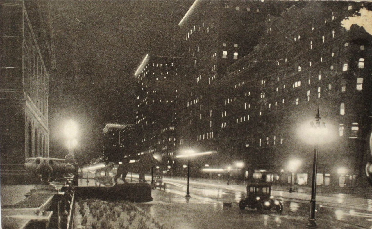 Black-and-white photo of a dark, snowy night on Michigan Avenue, where the Art Institute lion sculptures face rows of buildings lit only by squares of light in the windows.