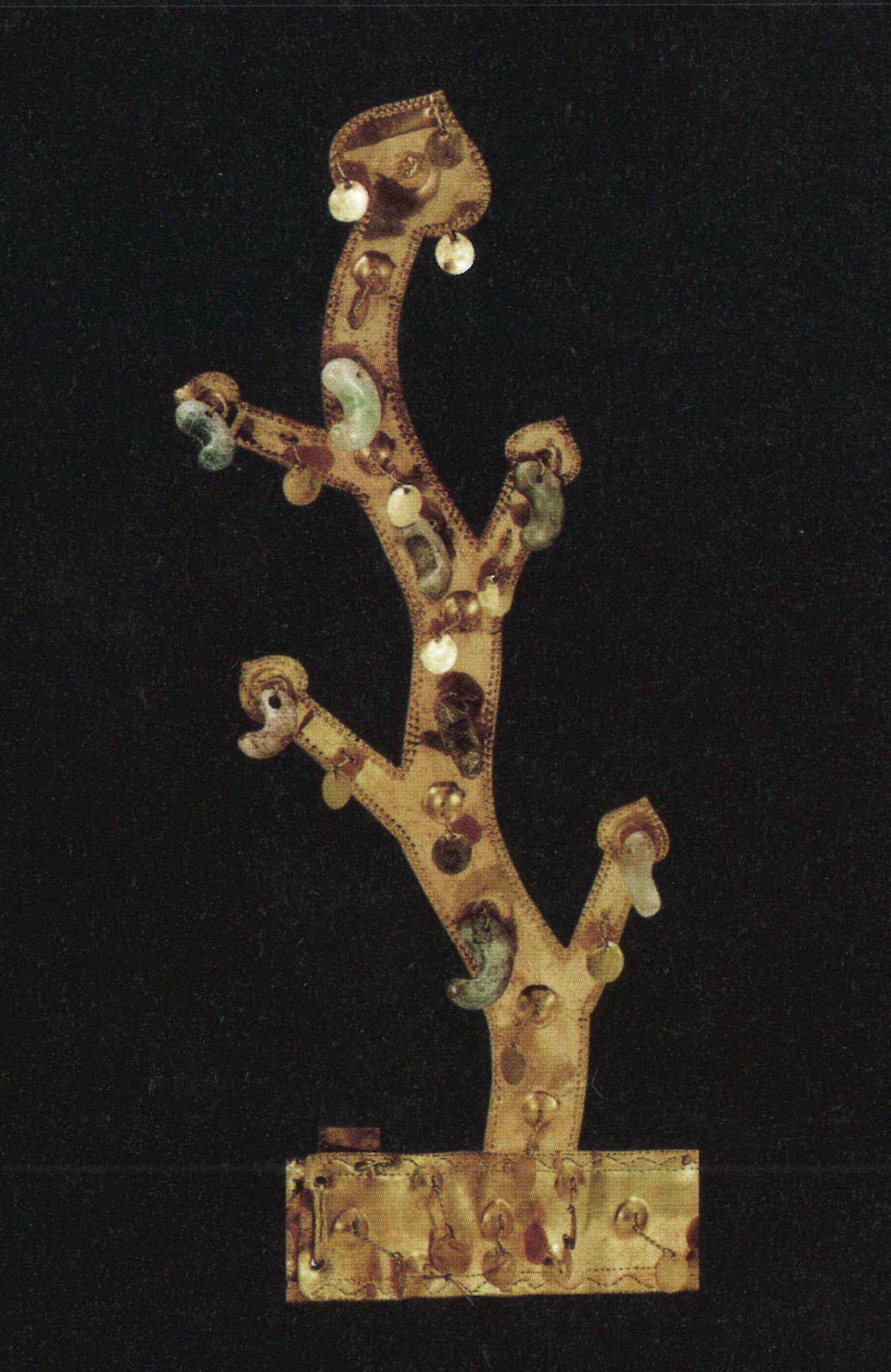 Photo shows one of the vertical elements of the gold crown. From a wavy central element, two short branches on each side extend outward. Beads and small gold discs hang from all parts of the antler shape.