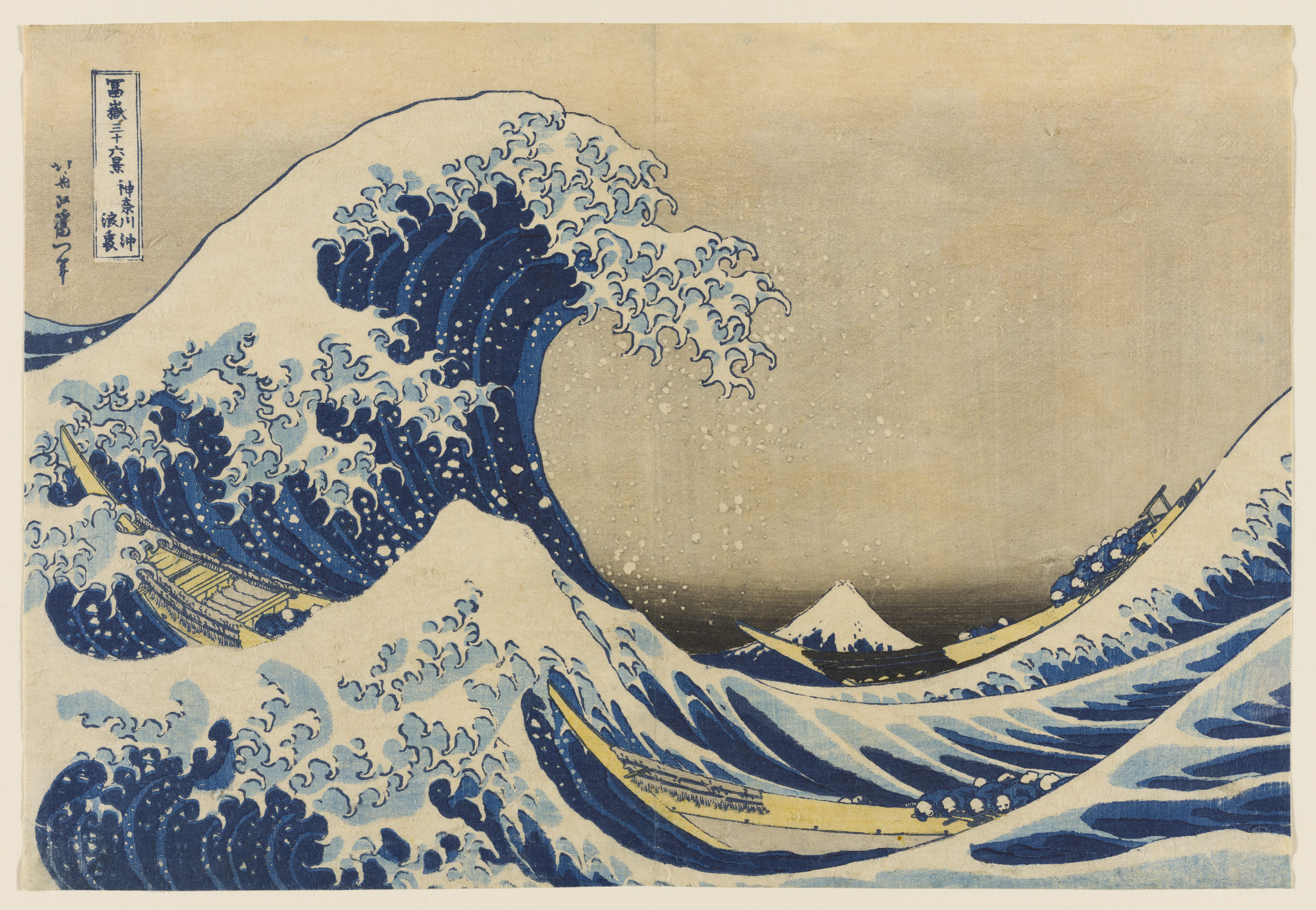 A color print features an enormous, highly animated wave with white peaks rising at left, poised to crash down at right. Beneath it is a long rowboat, and in the distance at right is a cone-shaped mountain, Mount Fuji.