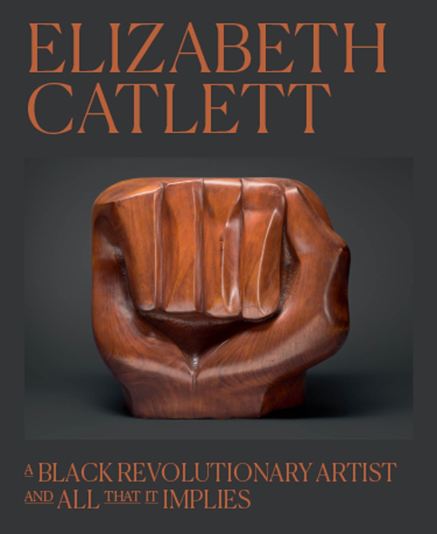 Photo of a black hardcover book with the words "Elizabeth Catlett" at top in capital letters and "A Black Revolutionary Artist and All That It Implies" below in sentence case. Between the two, at center, is a sculpture of a clenched fish made of varnished wood.