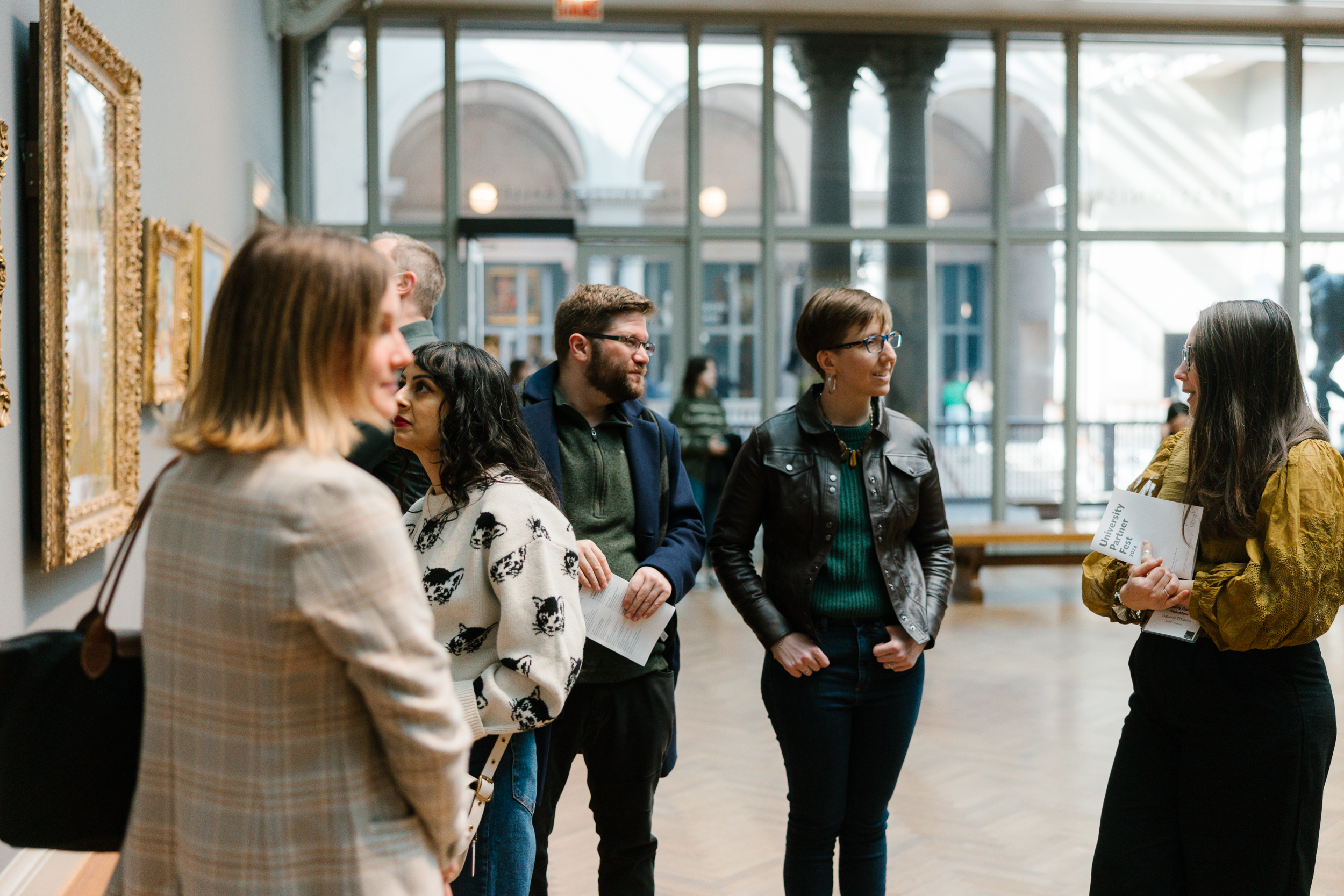 A photo taken in the Art Institute's Impressionism galleries shows a group of visitors smiling and engaging with a tour guide.