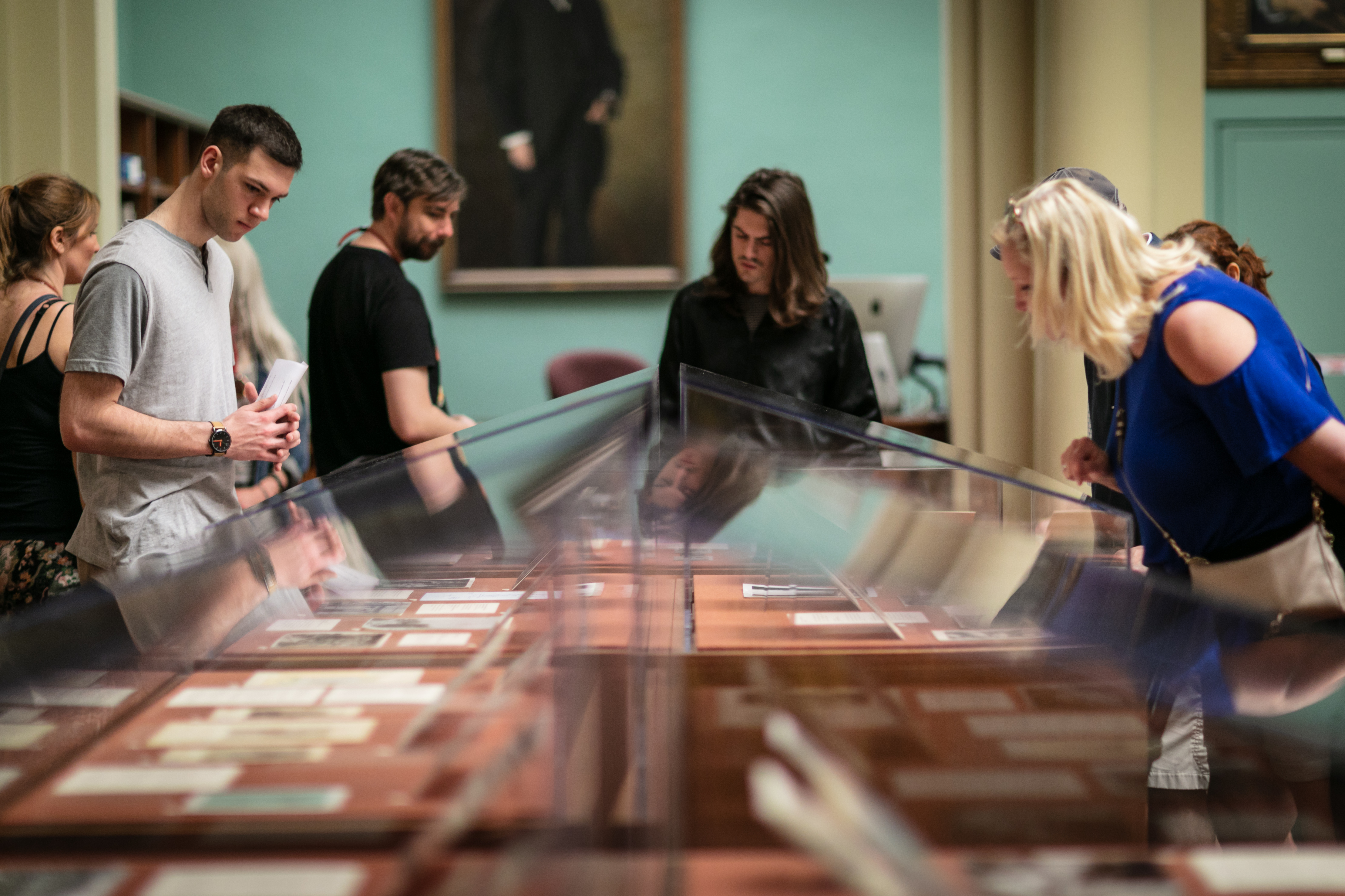 A group of people gathered around a glass case with documents.