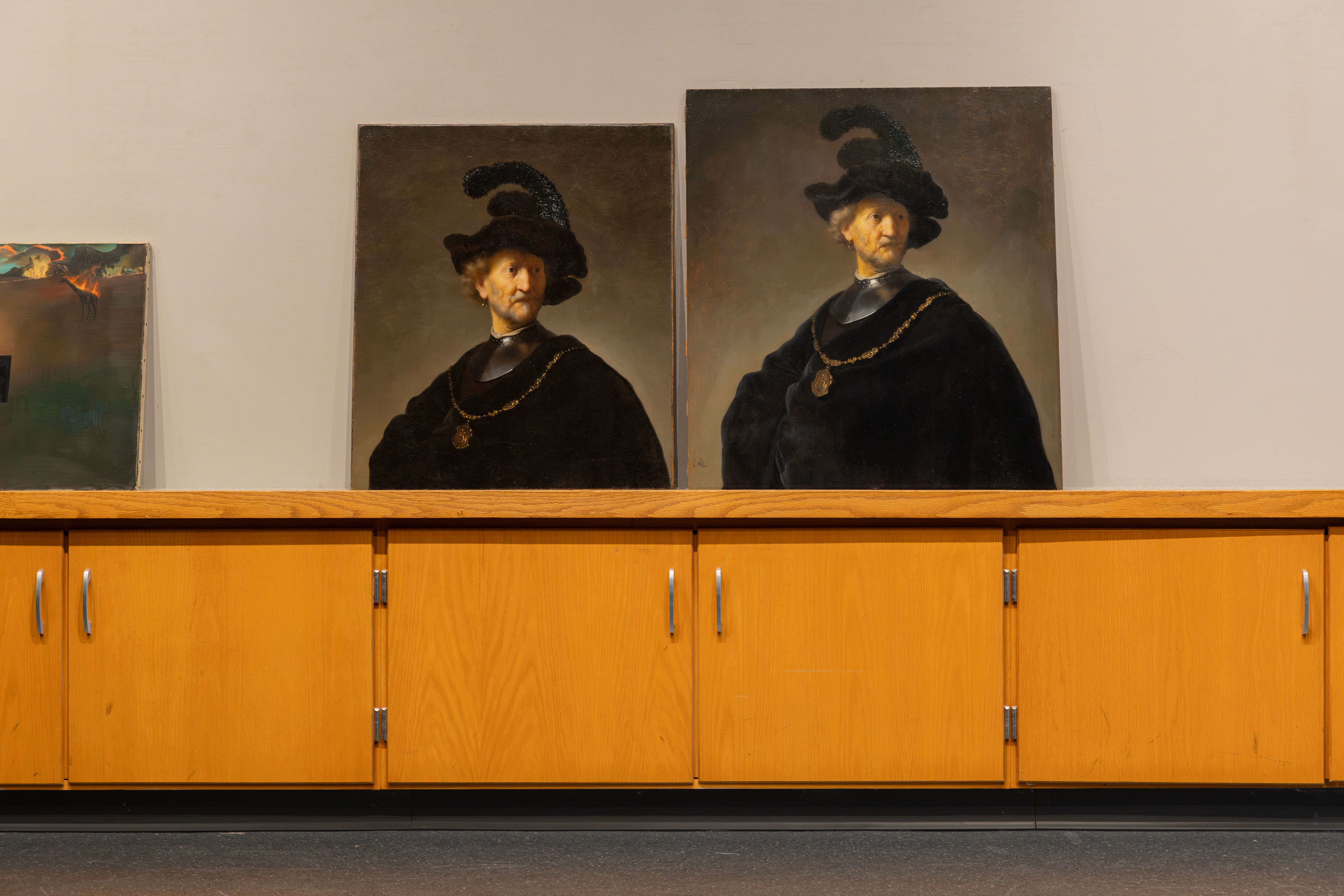 Two paintings of seemingly identical subjects sit side by side. In each a light-skinned older man with blond hair, beard, and mustache wears a deep-black cape and feathered hat, silver gorget, and wide gold necklace with a large pendant. The painting on the left is shorter, showing less of the subject's torso.