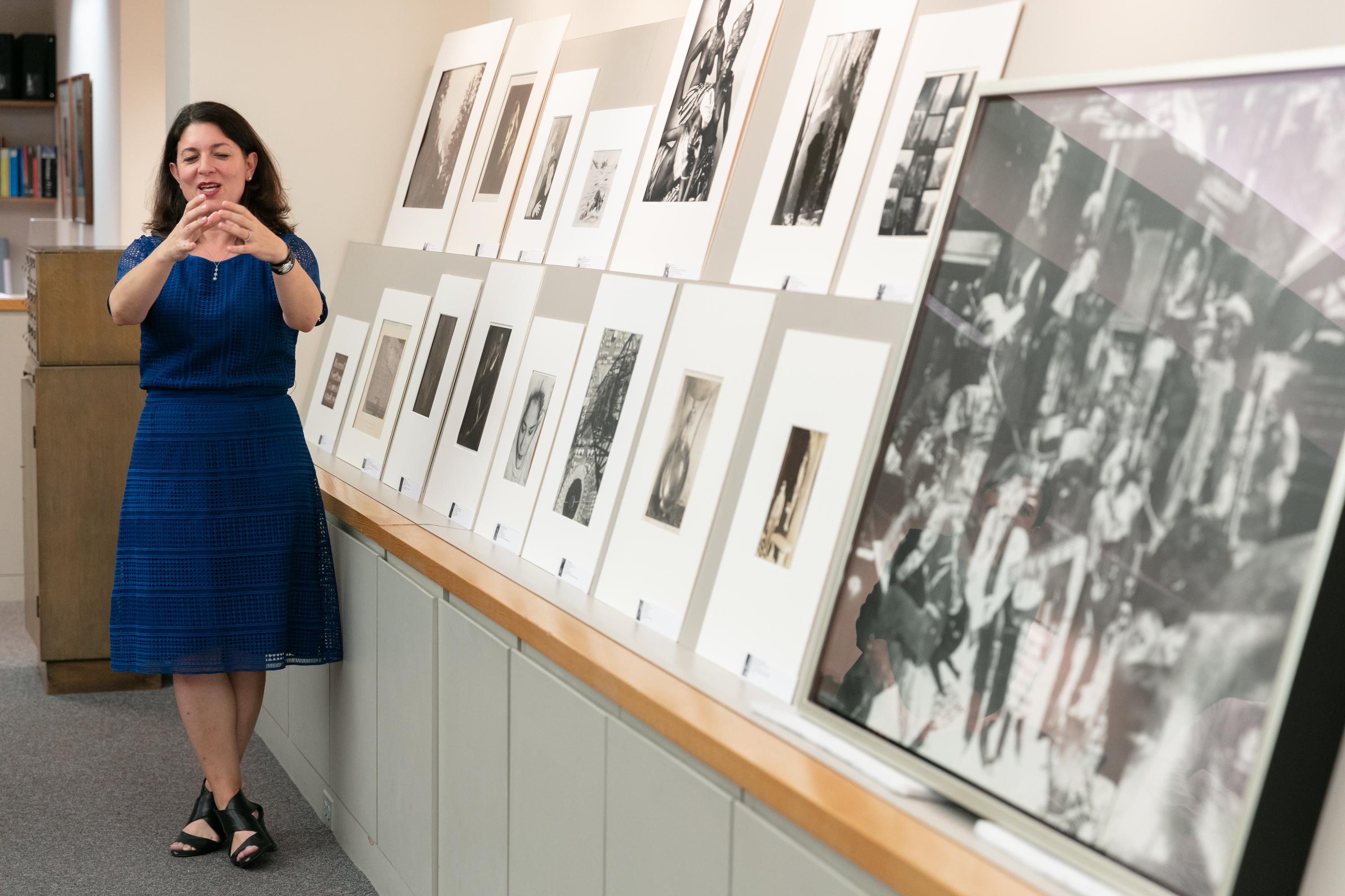 Curator Liz Siegel stands next to several photographs propped up on angled shelves in the photography study room.