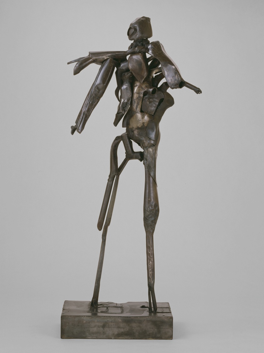 A metal sculpture of a man made up of disparate metal parts.