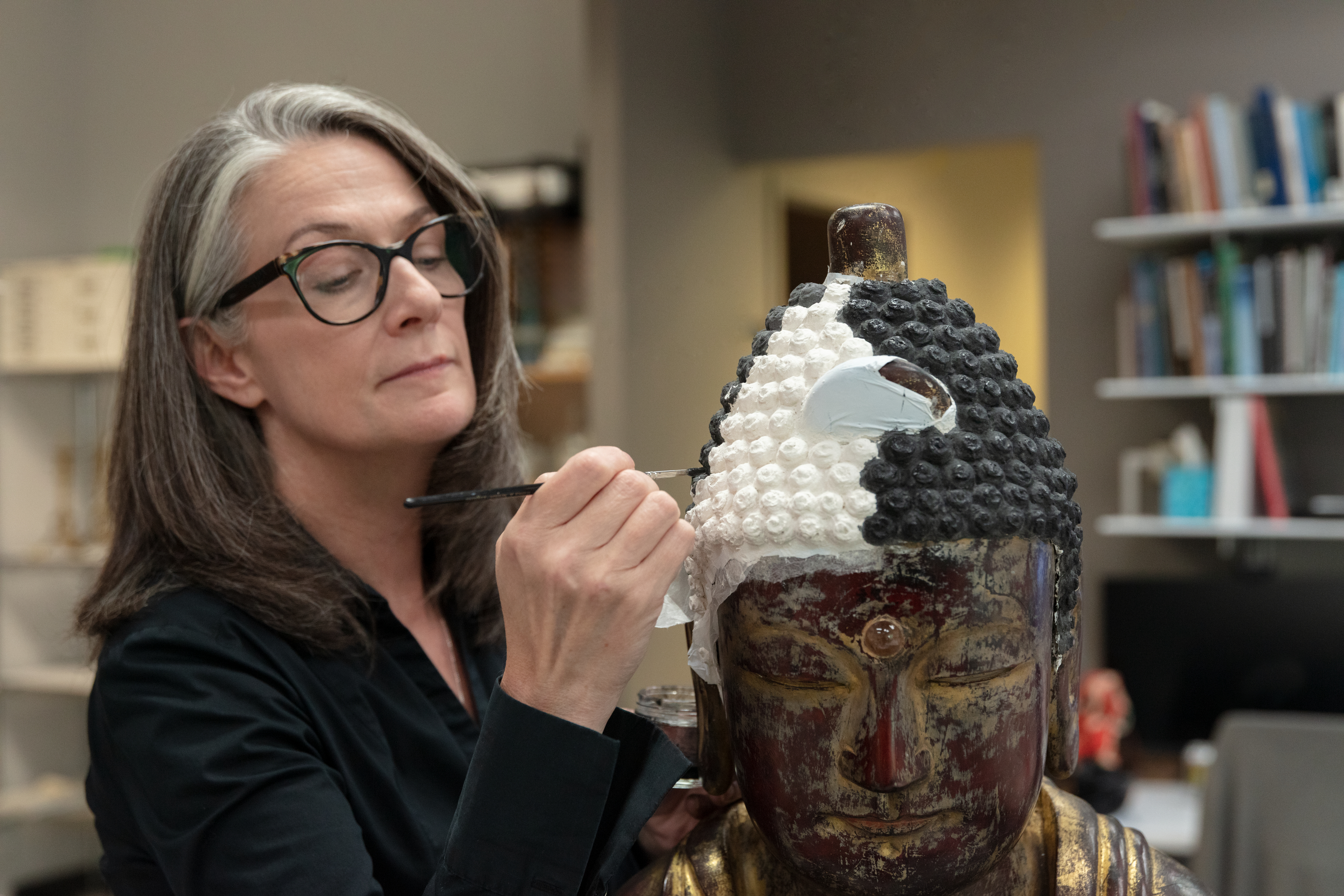 Conservator Lisa Ackerman paints the recreated hair of a 18th-century Joseon dynasty Buddha