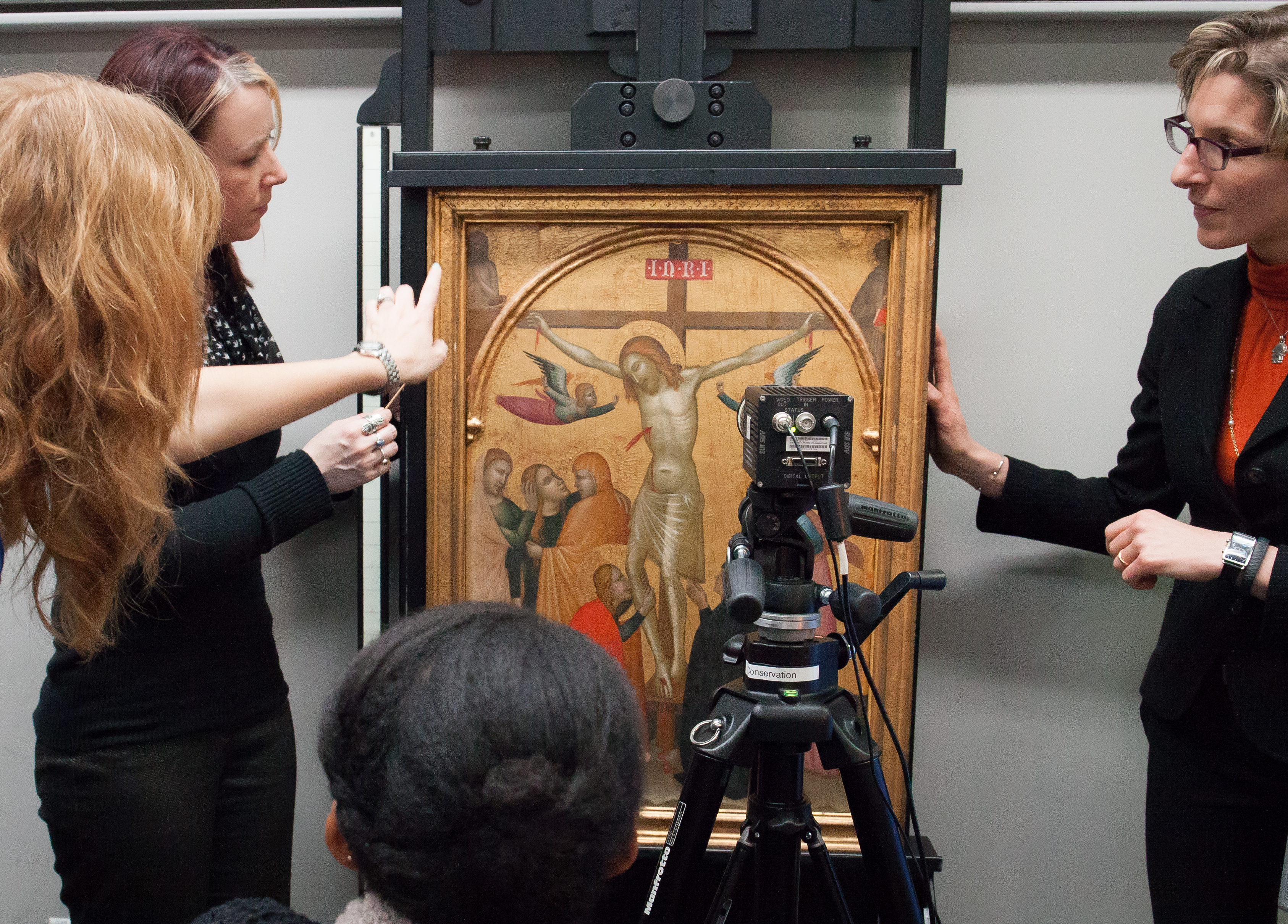 A conservator discusses a work of art with a small audience.