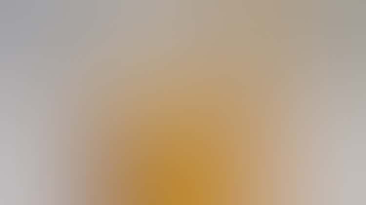 A clay sculpture the color of goldenrod with the appearance of thick cloth wrapped up around a tall bowl and knotted at the top.