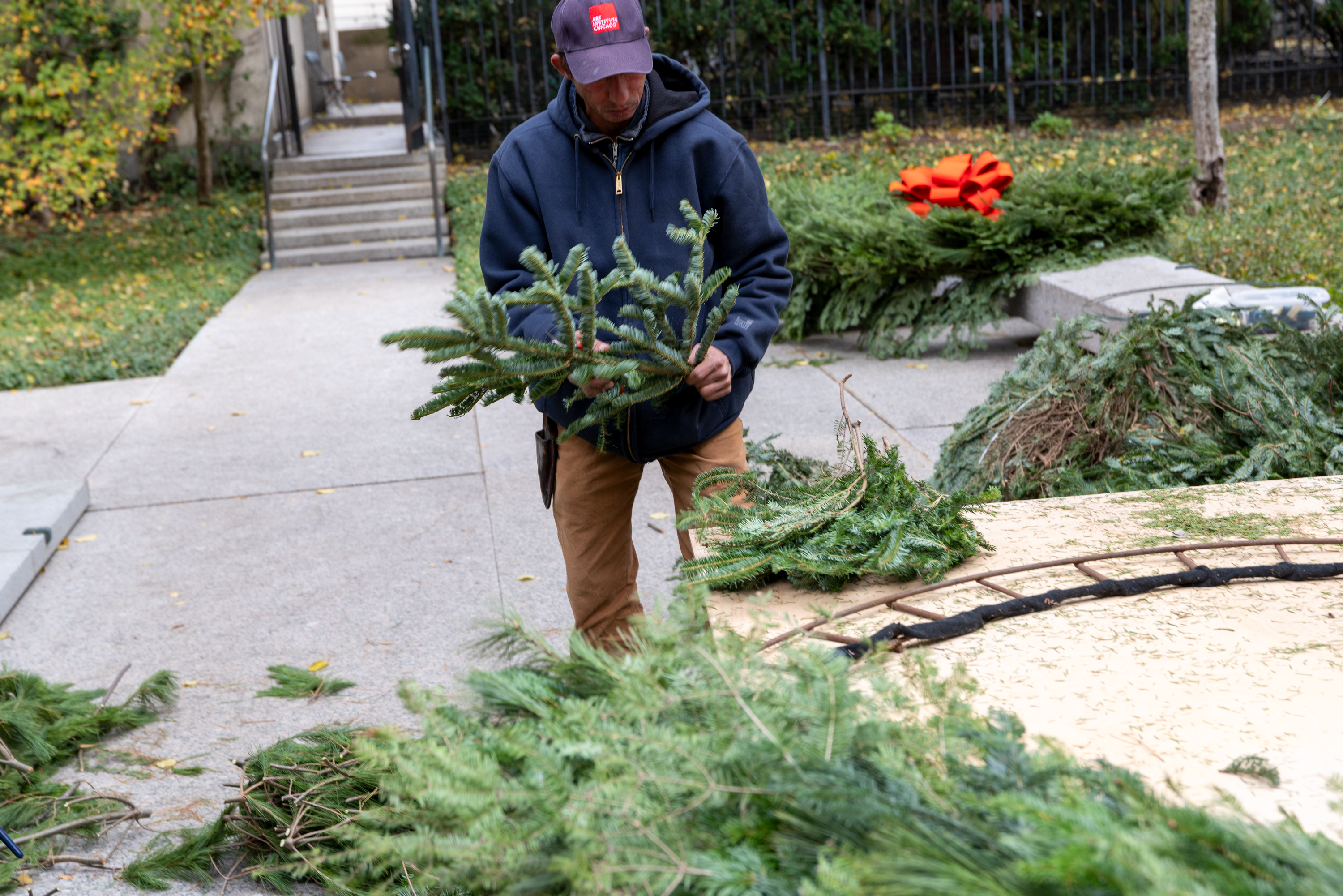 Photo shows a slim man carrying an evergreen branch.