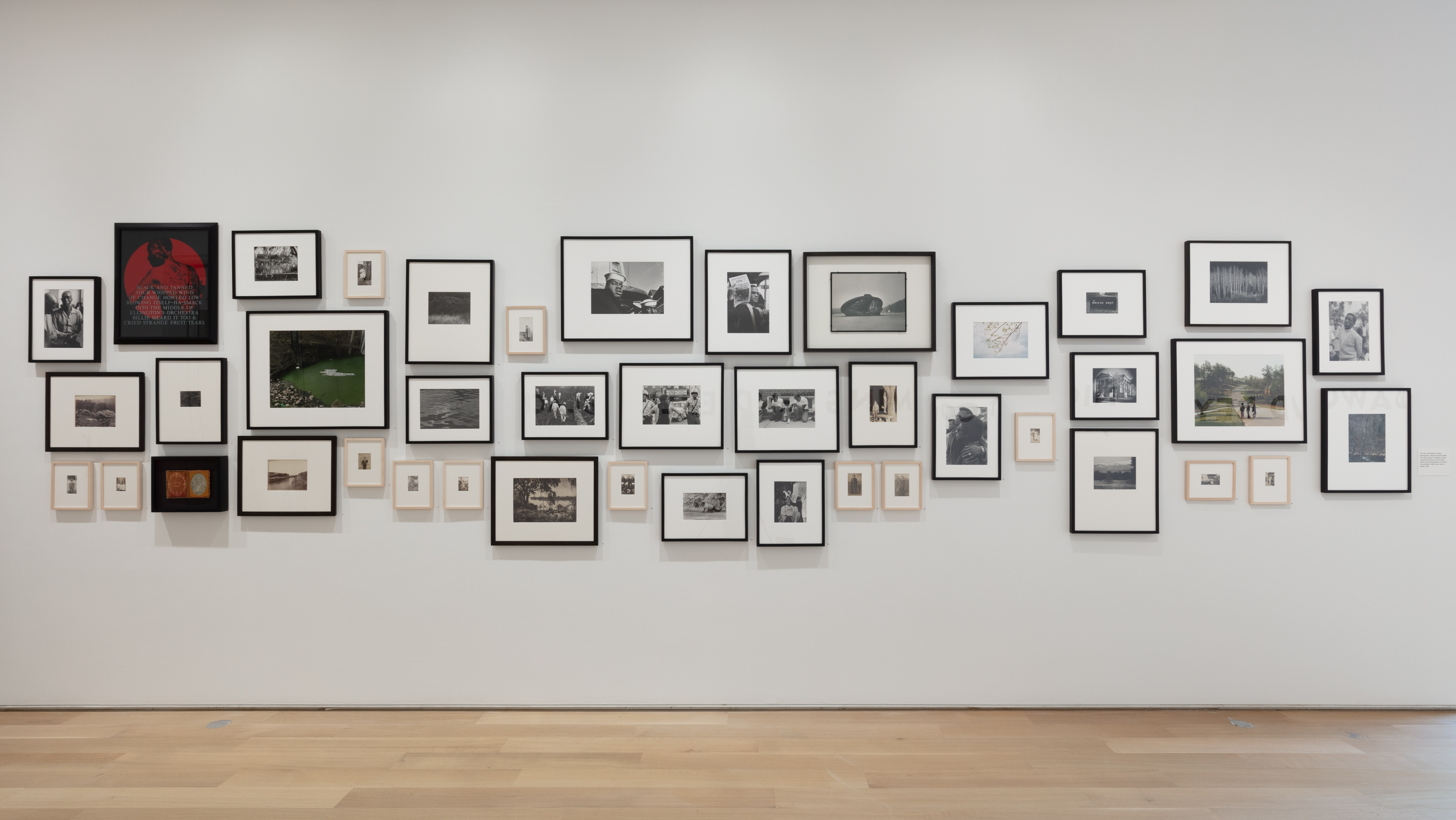 Wall of photographs from the collection selected by Dawoud Bey to accompany his exhibition Night Coming Tenderly Black
