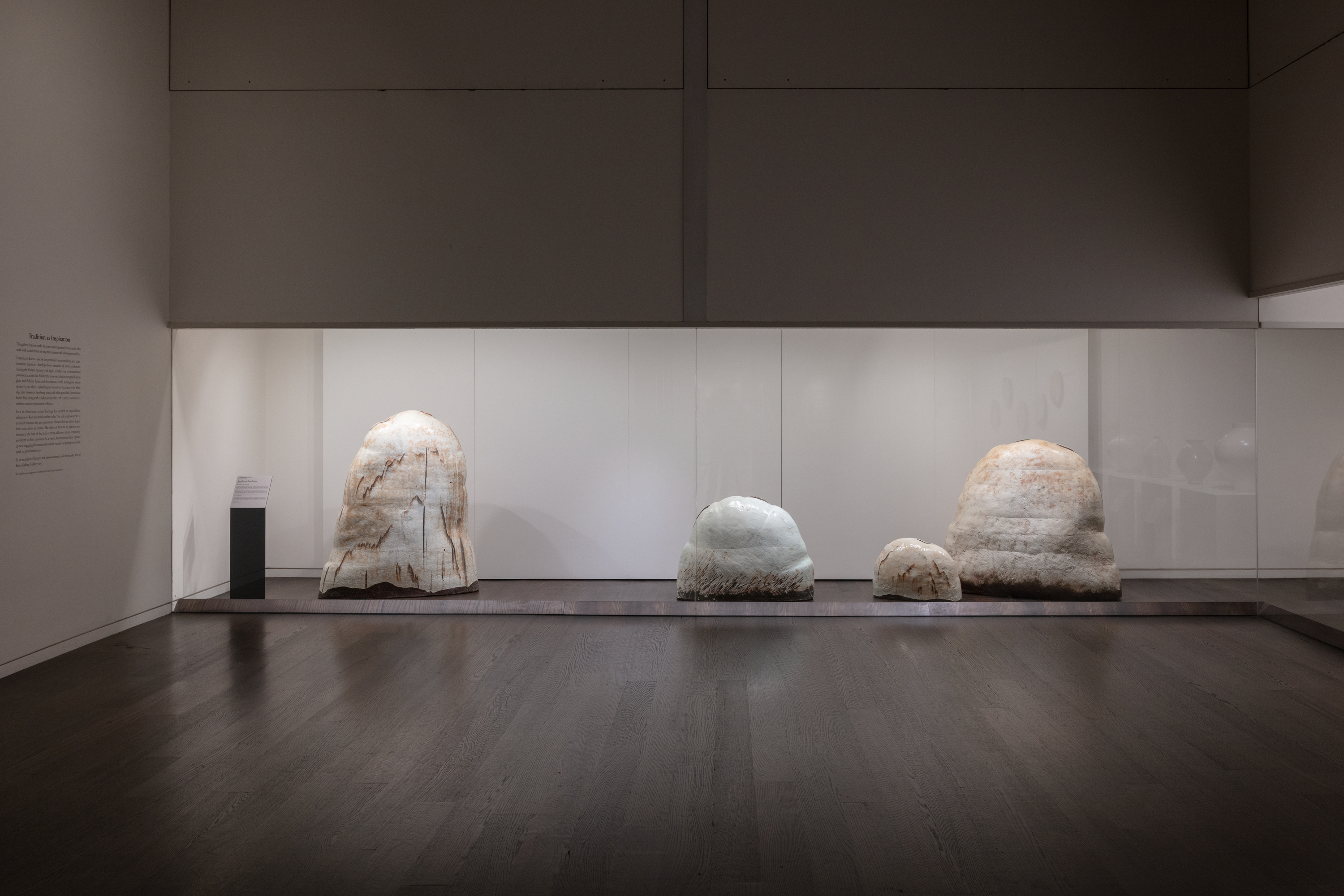 Photo shows an art gallery with four sculptures arranged behind glass. The sculptures vary in size, but all have a similar organic form resembling a domed rock formation.