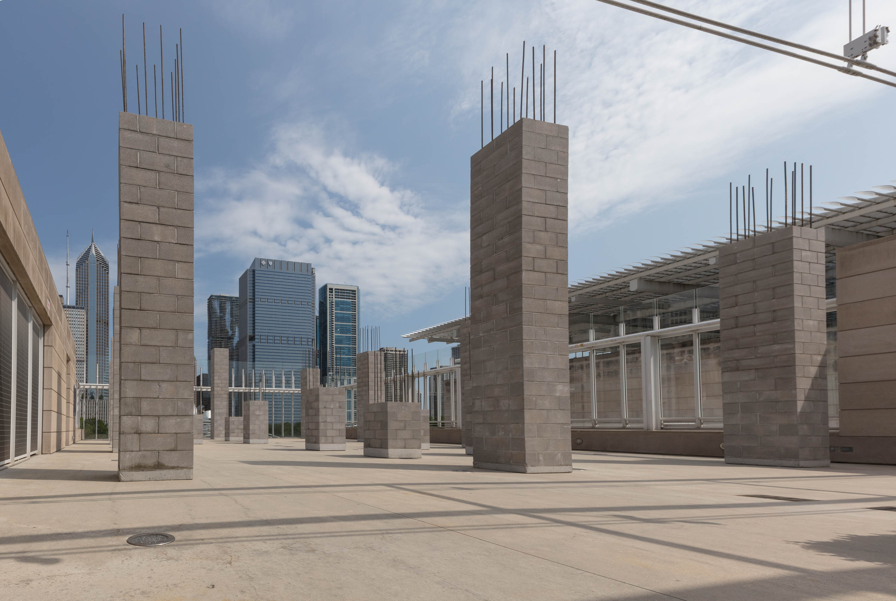The 3rd-floor terrace of the museum features towers of cinder block with rebar coming out the top. The city skyline can be seen in the background.