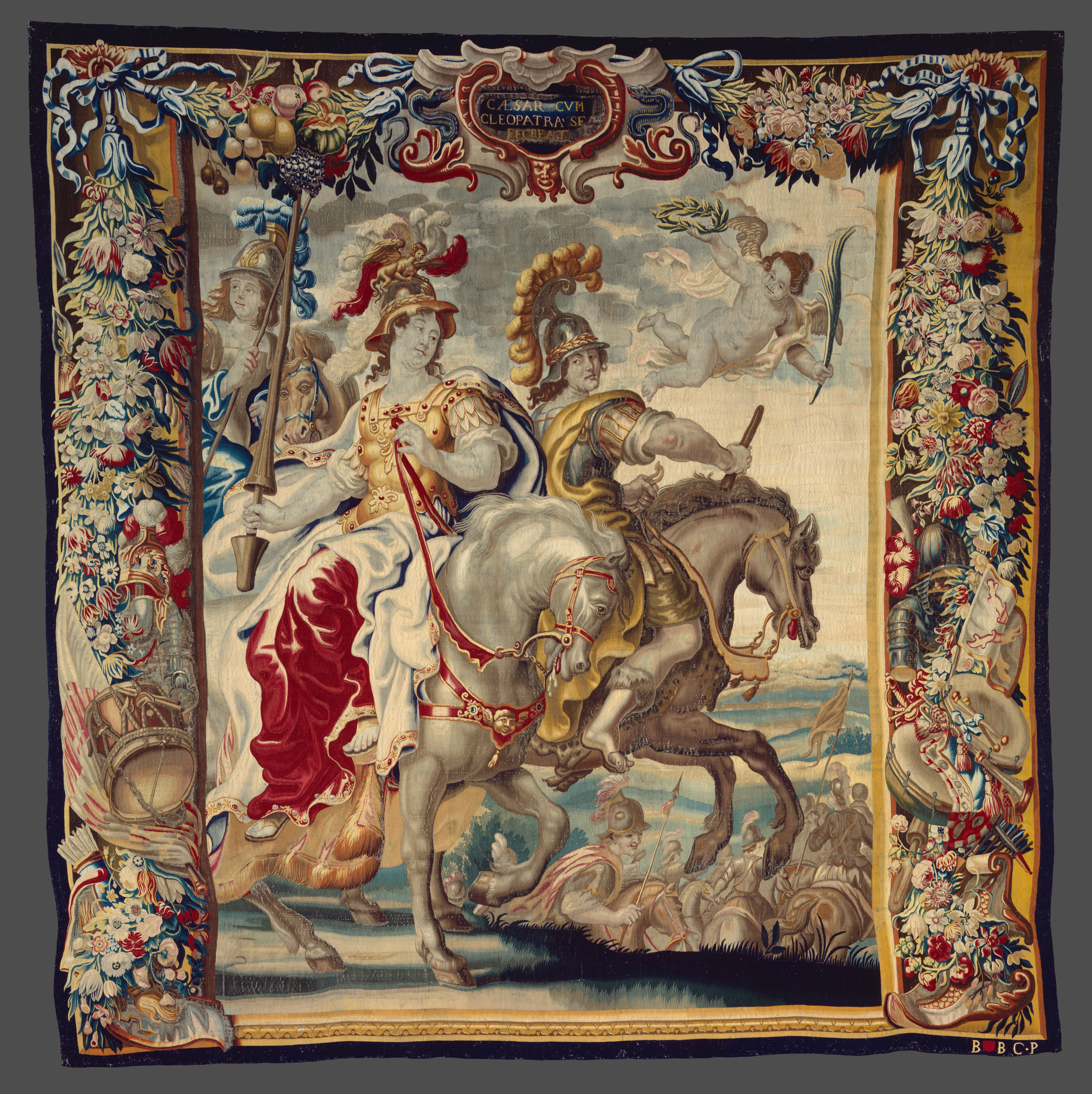 A large tapestry with an ornate border featuring two men on horseback.