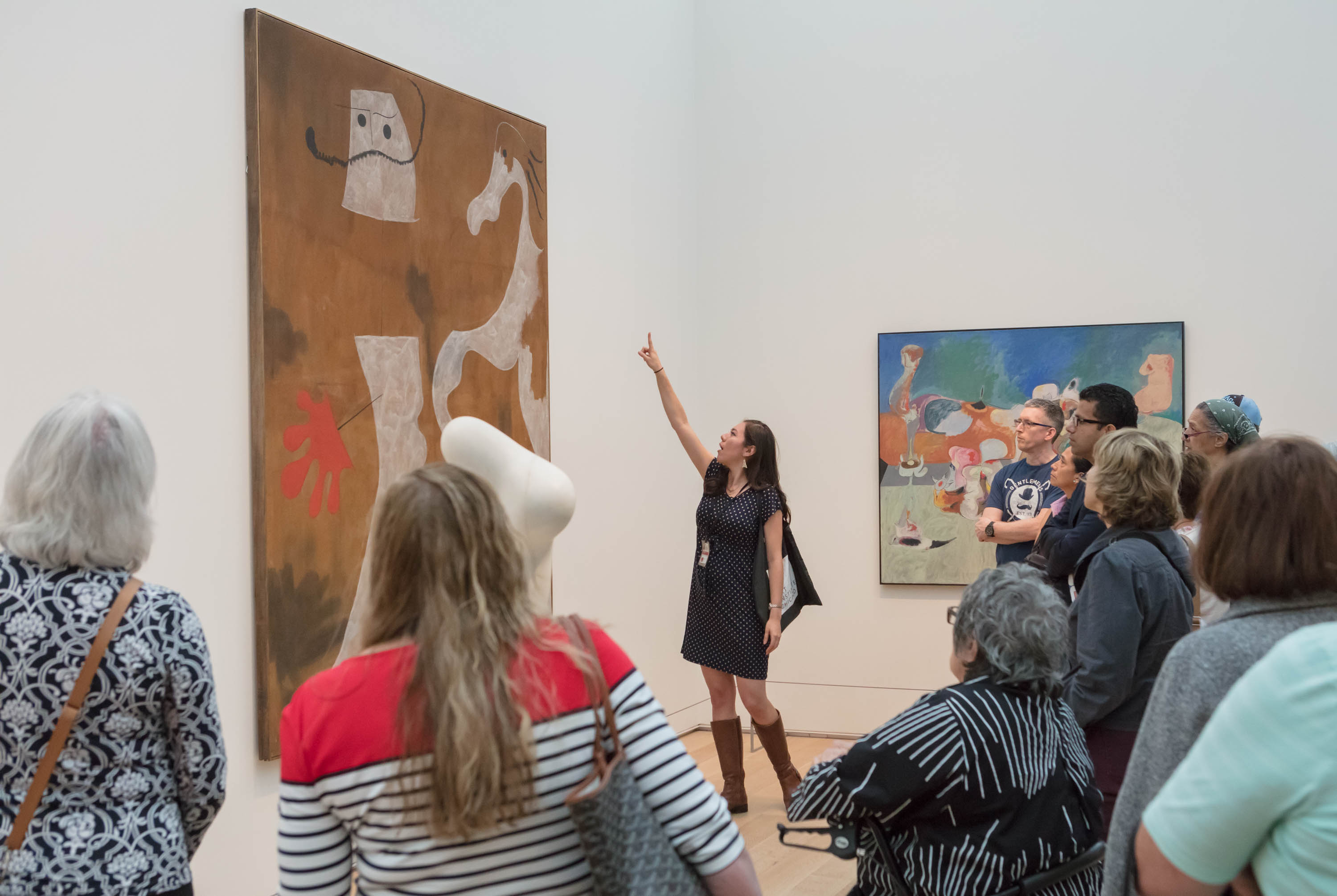 Adult learning educator Paulina Lopez points at Joan Miró's The Policeman to discuss it in front visitors during a gallery talk.