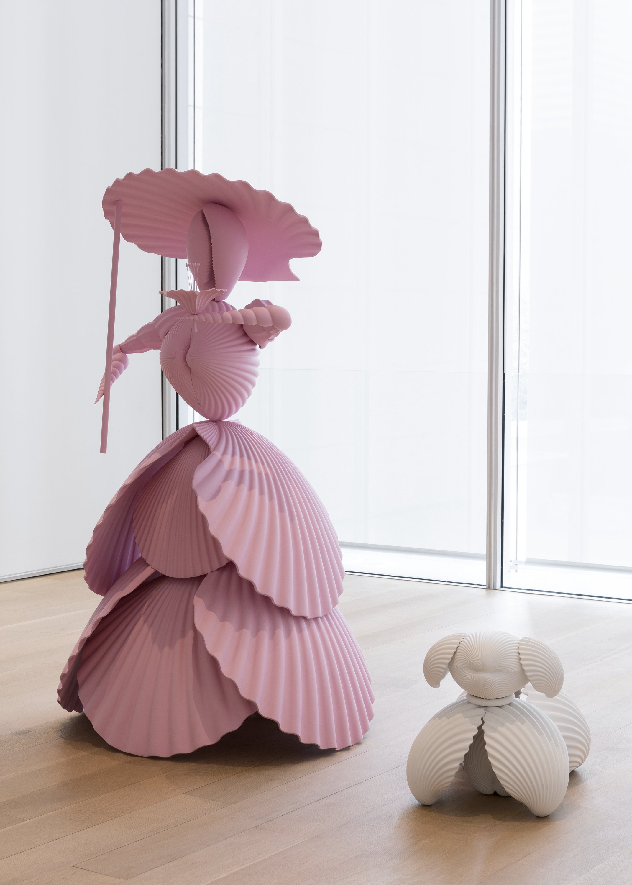 Pink sculpture of a woman, whose form is made out of a seashells. A small white dog is next to her, also made out of sculpted seashell forms.
