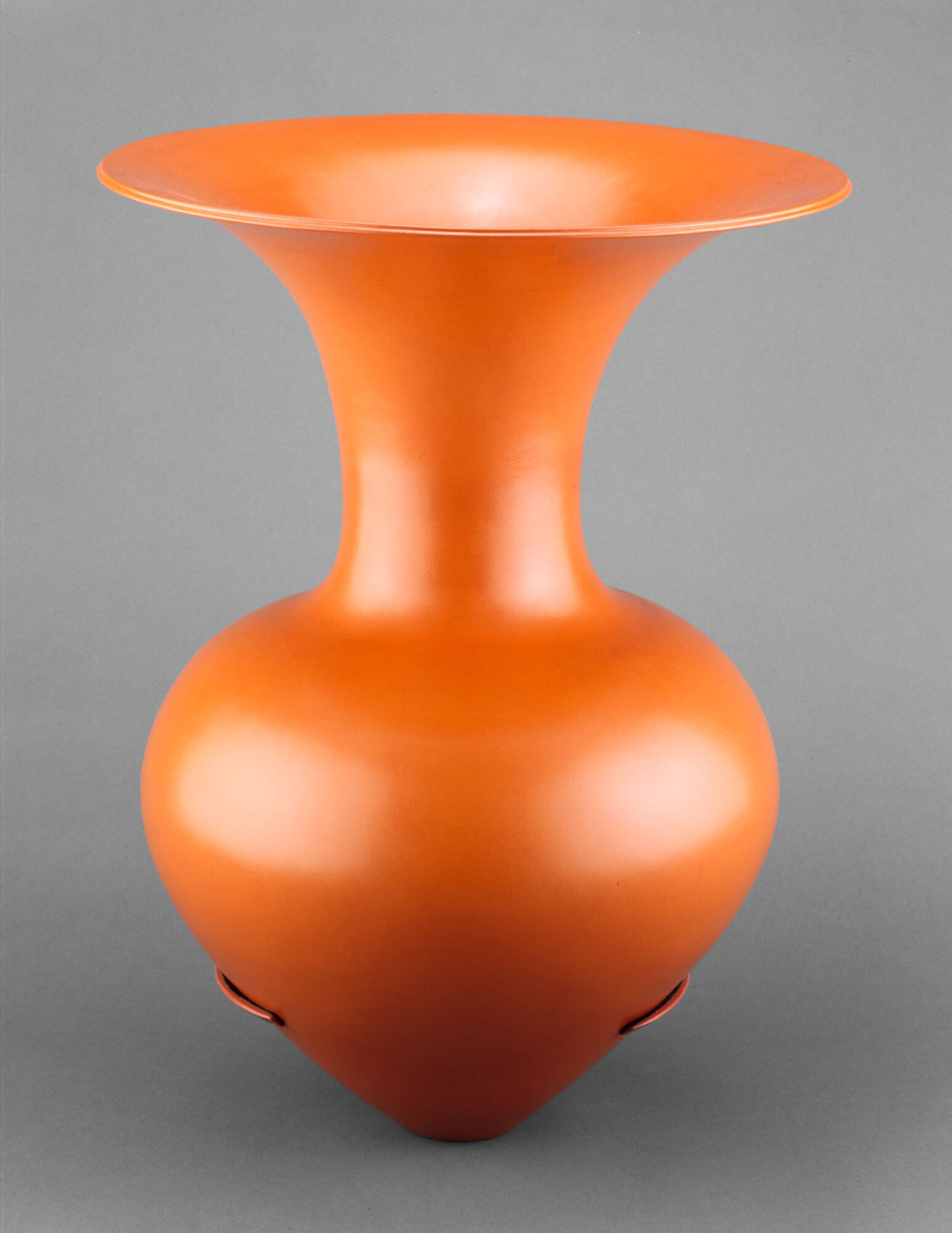A shiny, burnished orange vessel with a pointed base that widens into a round shape, narrows into a narrow neck, and widens again into wide opening with a upward-facing rim.