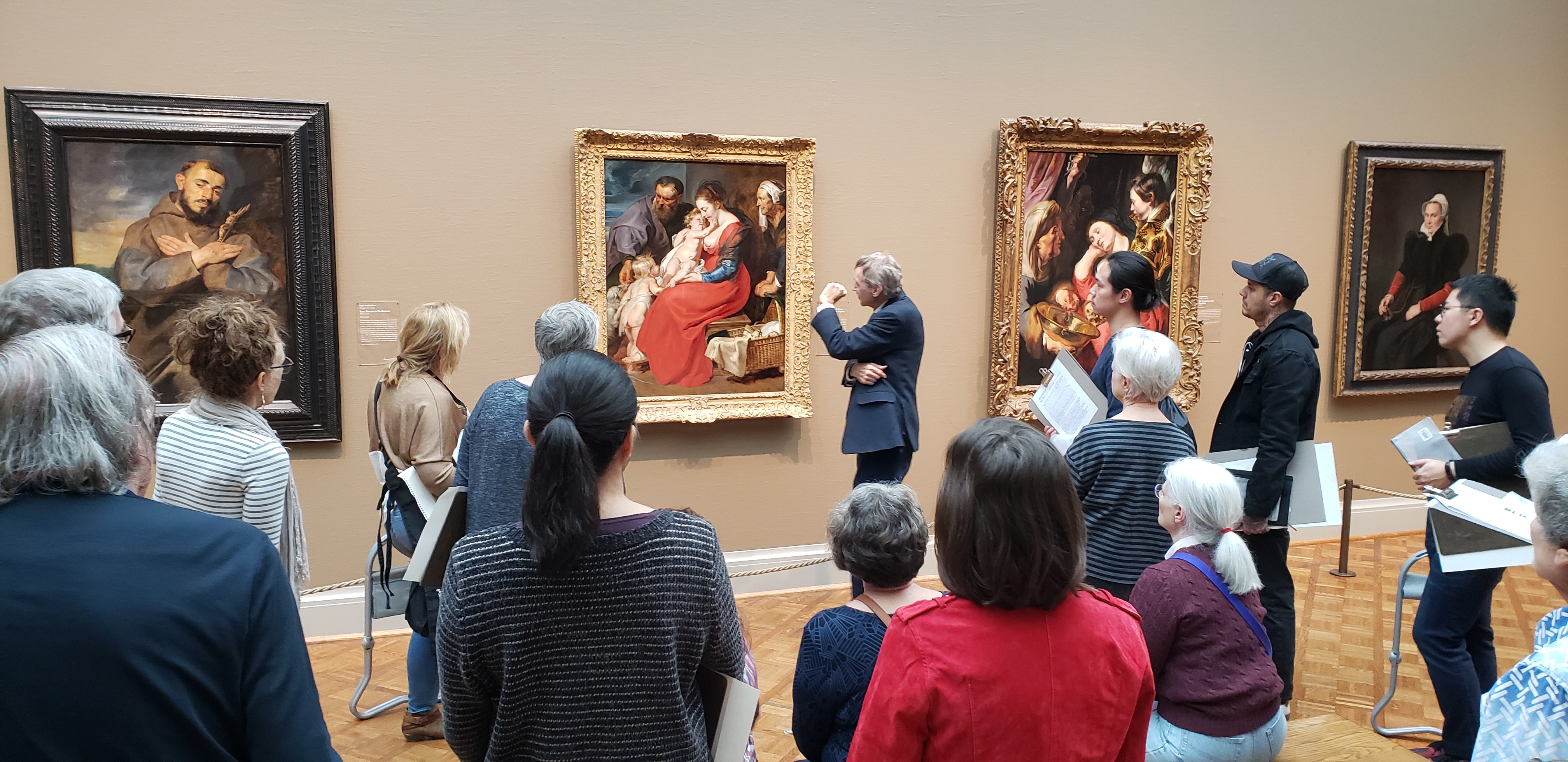 Instructor Mark Krisco stands in front of a work of art to point out details to a group of students.