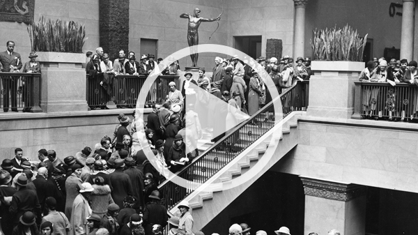 A black-and-white image shows a large crowd of people ascending the museum's Grand Staircase.