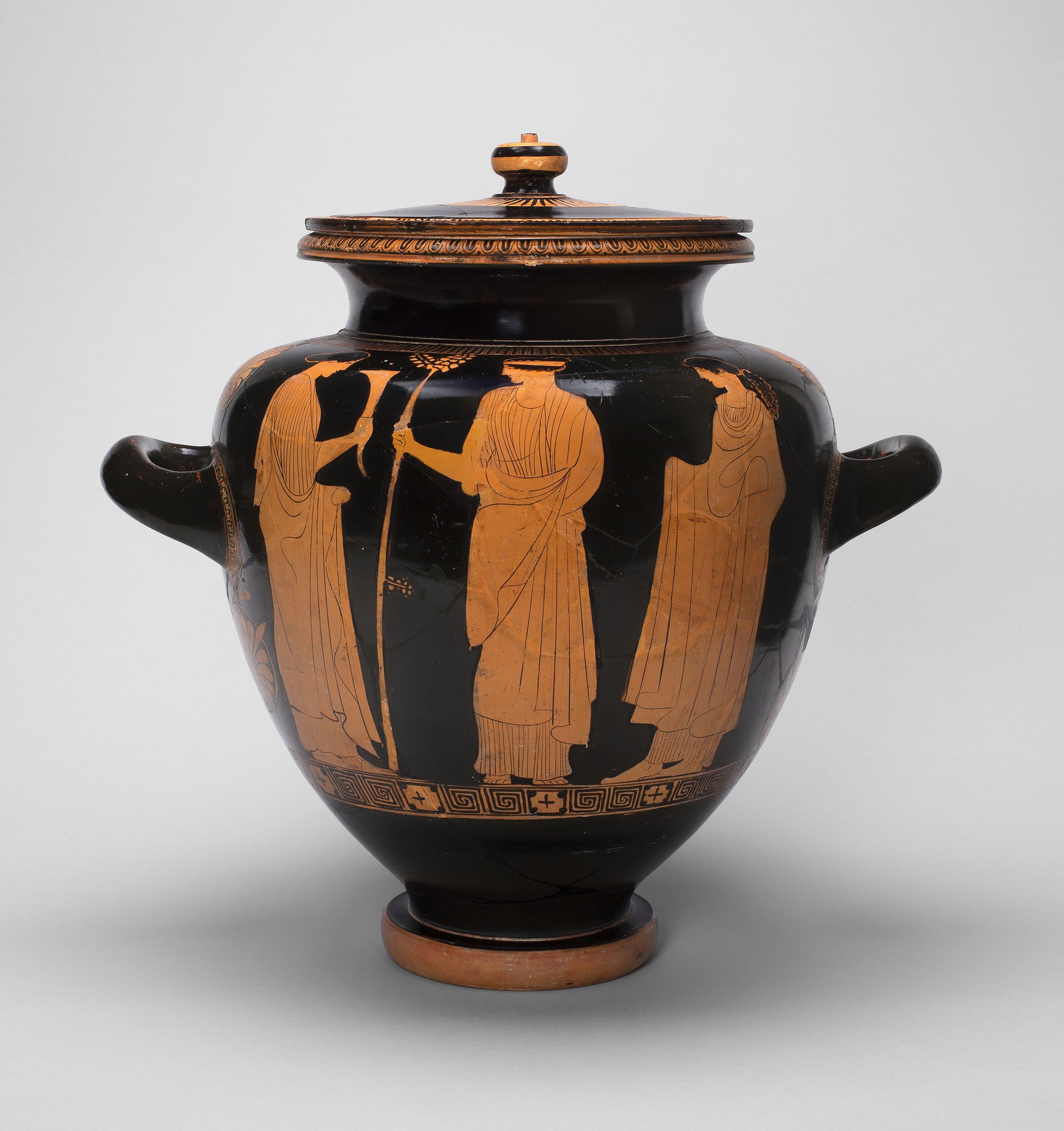 An ancient Greek vase is shown. The vase is painted with a depiction of human figures.