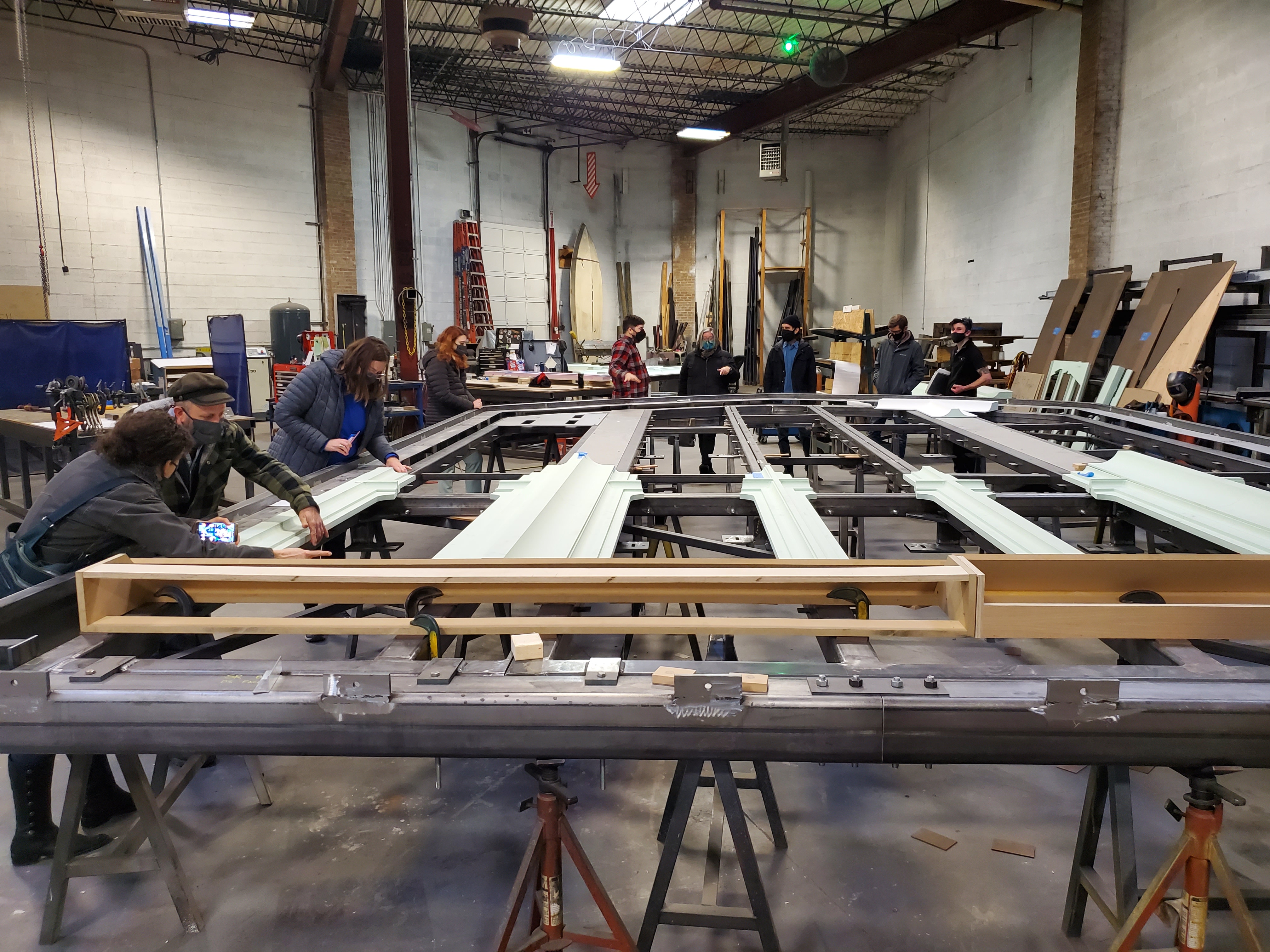 A few Art Institute staff members lean over an immense table that holds part of the structure that will hold all 46 panels of the Tiffany window.