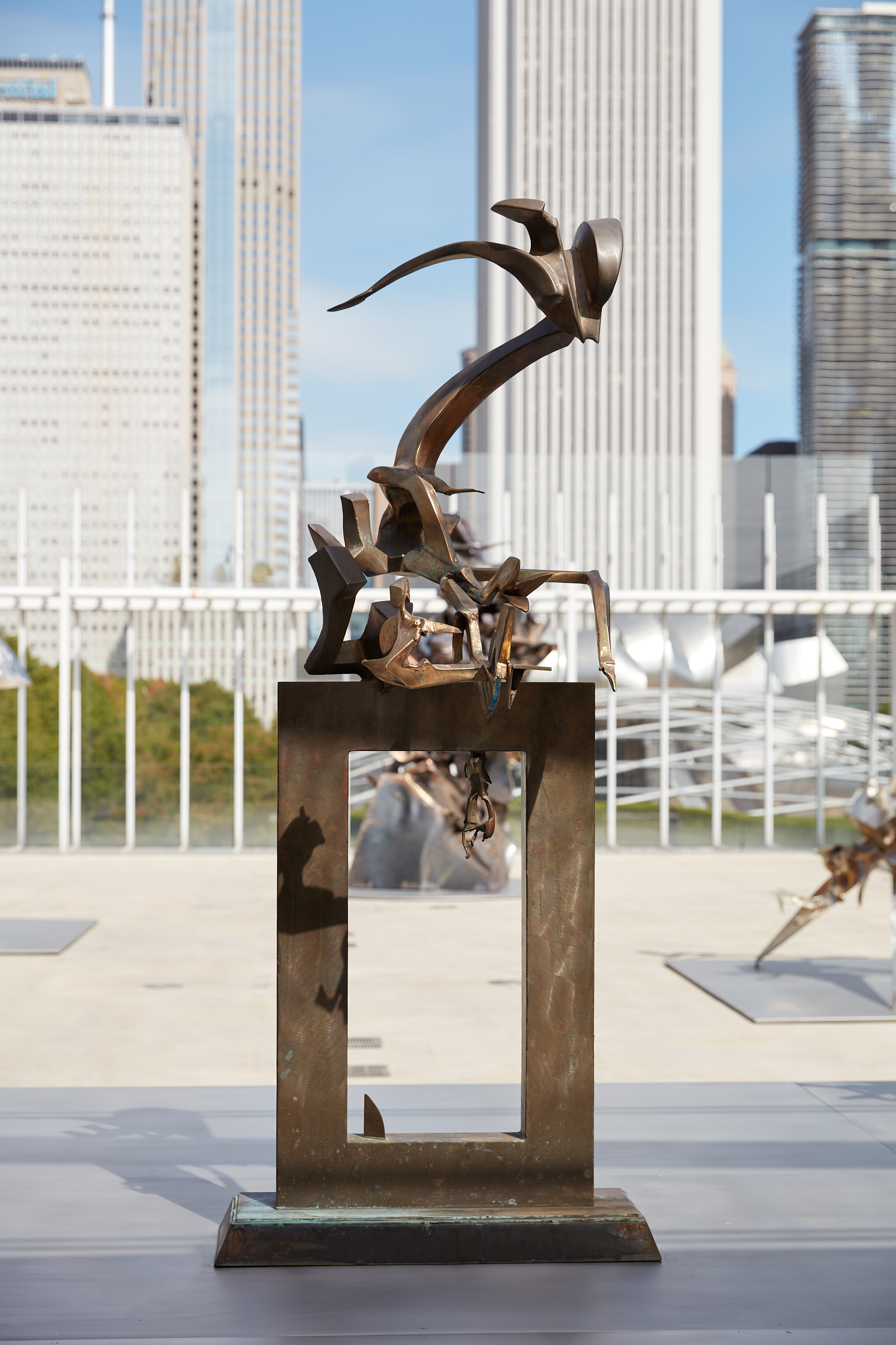 A metal sculpture, its base a hollowed rectangle. Atop twisting and turning irregular branching forms emerge.