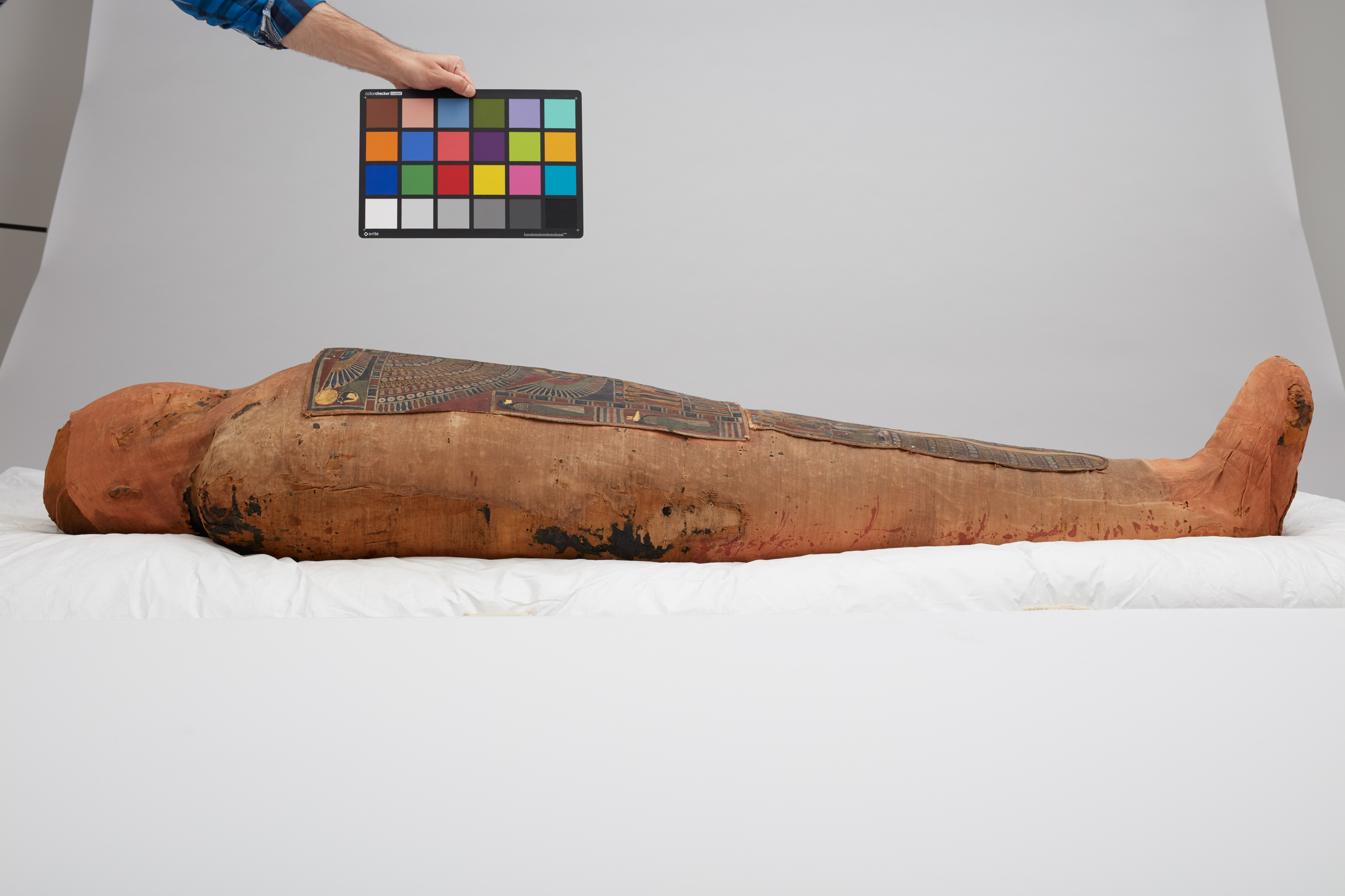 Mummy laid out on white fabric in perparation of being photographed