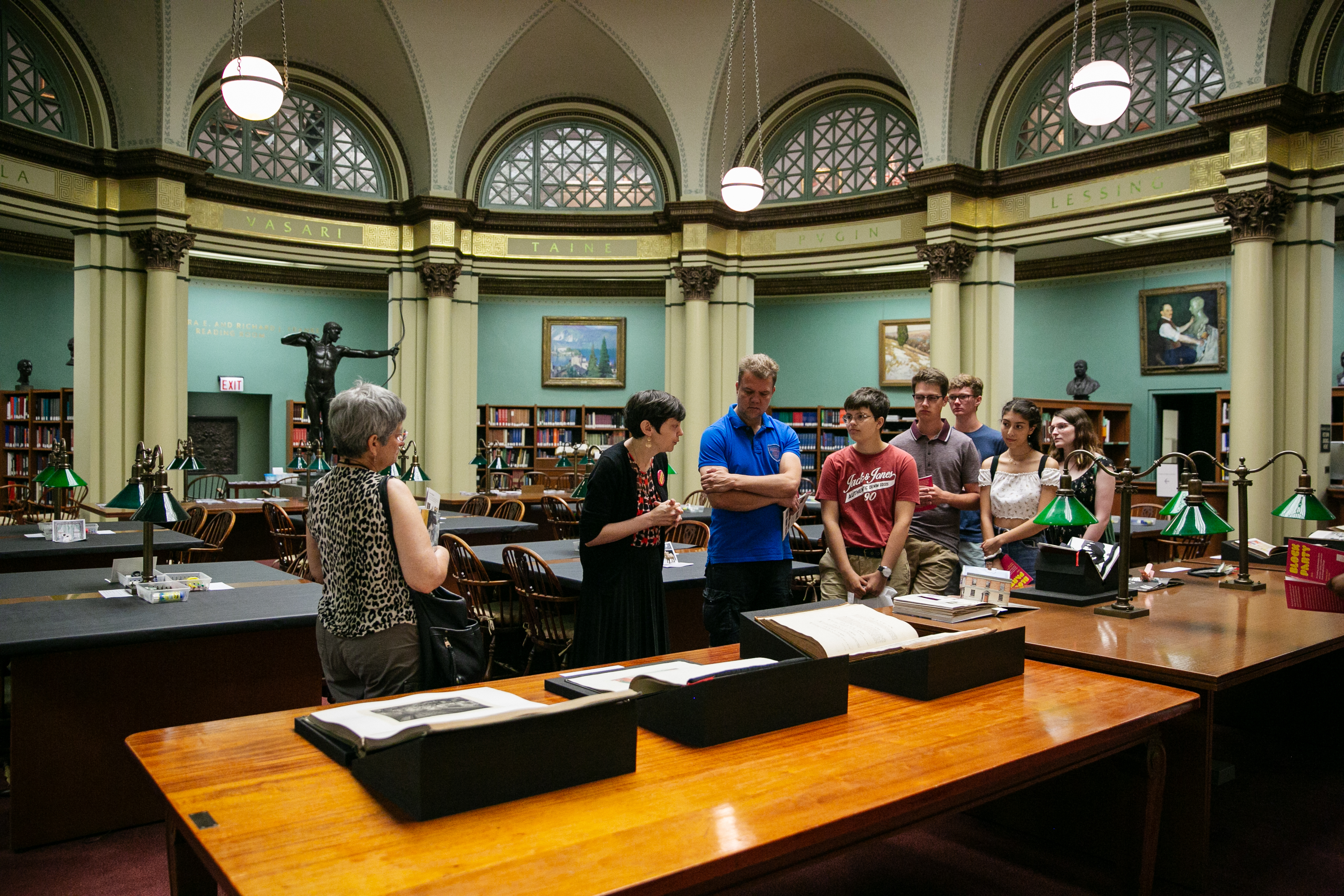 A photograph of the library reading room shows several people looking at archival materials displayed on the wooden tables.