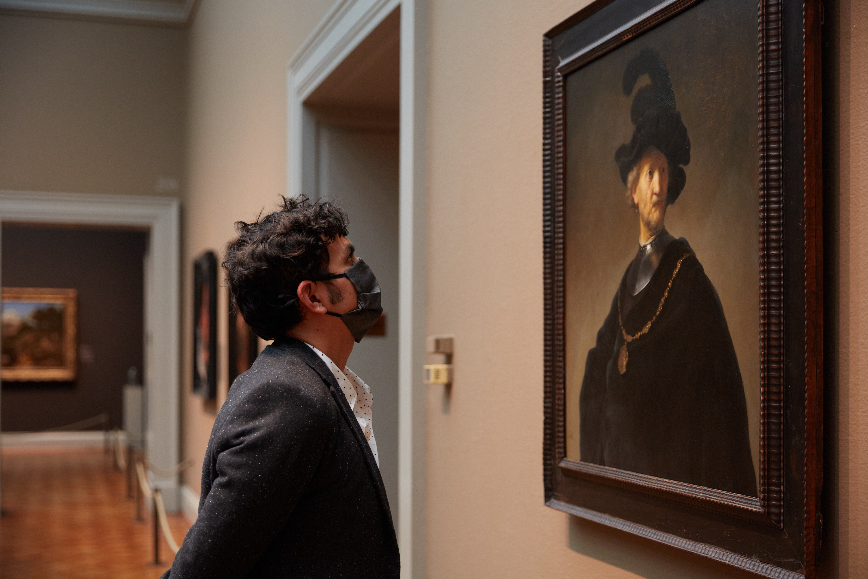 Photograph of associate director Sam Ramos viewing Rembrandt van Rijn's painting "Old Man with a Gold Chain."