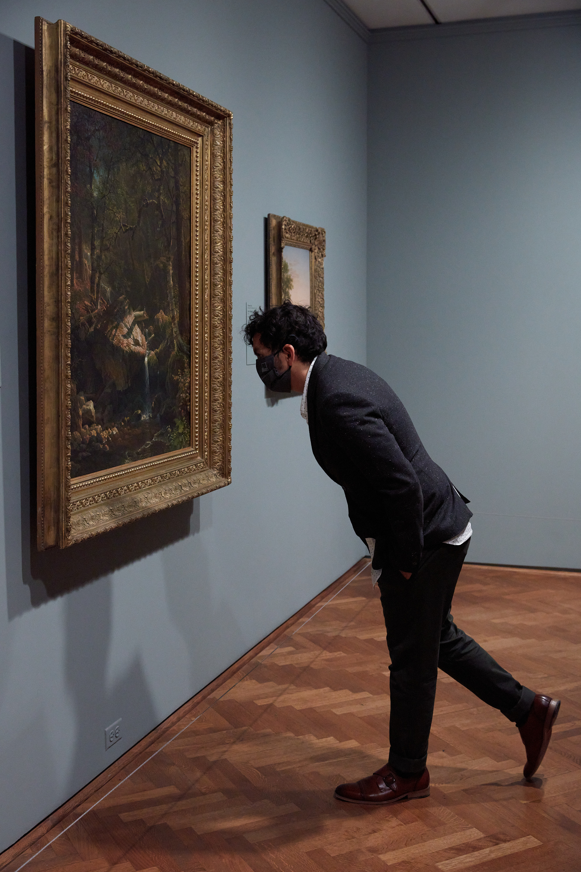 Photograph of Associate Director of Innovation and Creativity Sam Ramos leaning in to view a painting.